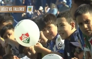 Em jogo do Vélez, crianças são vistas com bolas com o símbolo do Fluminense